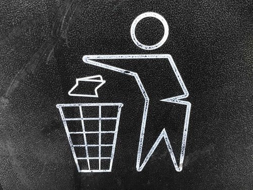 Chalk drawing of a person recycling a piece of paper into a bin, representing eco-friendly practices and the importance of recycling resources.