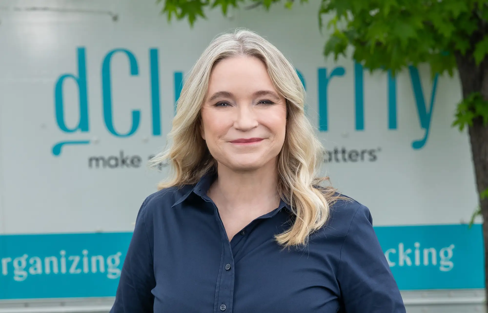 Headshot of Tracy McCubbin smiling and standing in front of the dClutterfly truck.