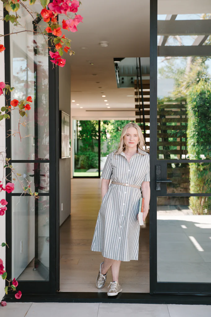 Tracy McCubbin is wearing the Robbi Striped Shirt Dress from La Peony Clothing for a photoshoot holding her decluttering and organizing books.